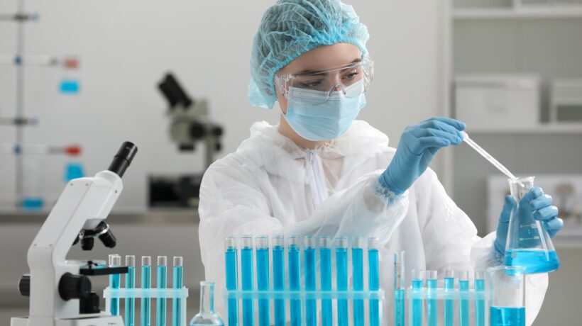 Scientist dripping sample into flask in laboratory